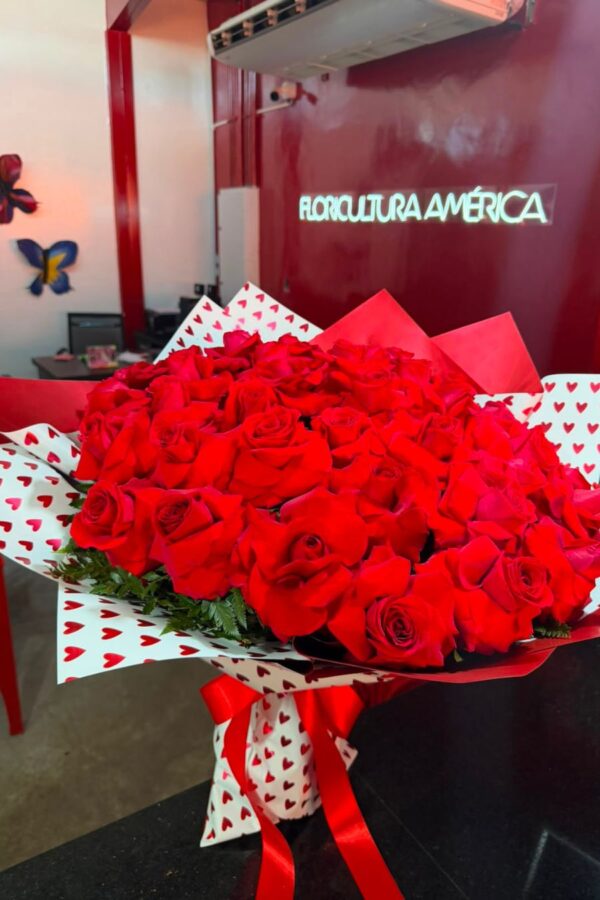 Buquê Quero Você com 50 rosas vermelhas colombianas importadas em embalagem com corações e laço de cetim